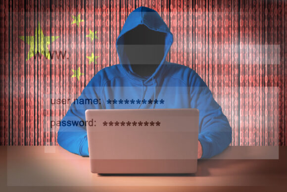A hacker sitting in front of a laptop on the background of digital flag of China. Cyber Security concept.